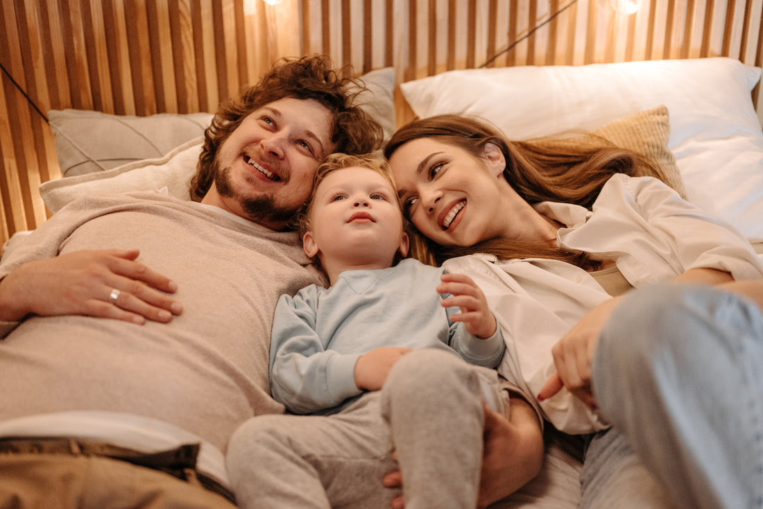 A happy family smiles together while they cuddle in bed