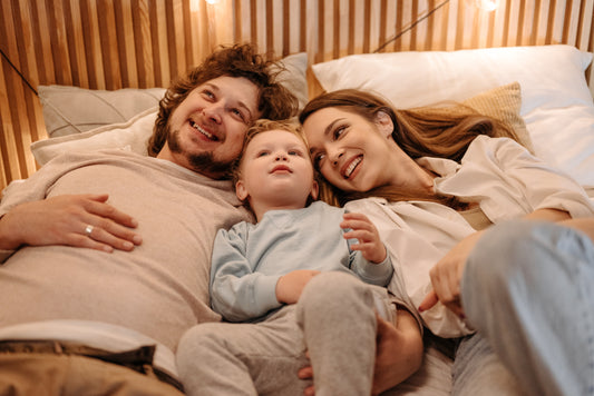 A happy family smiles together while they cuddle in bed