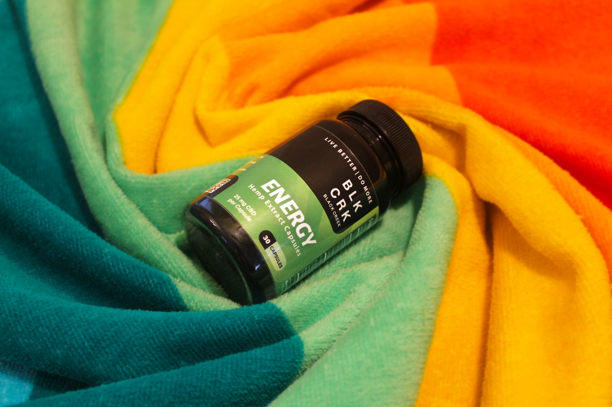 The Black Creek CBD Energy Capsules are swirled in a colorful beach towel
