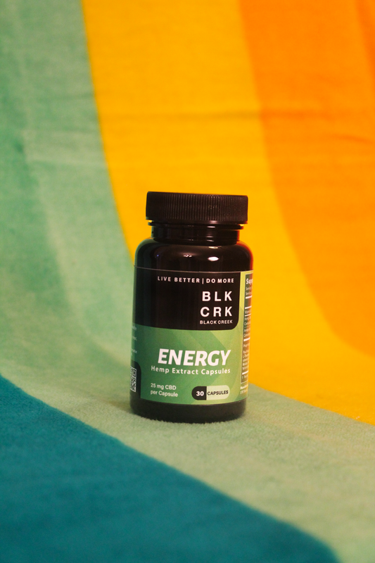 The Black Creek CBD Energy Capsules standing atop a colorful beach towel