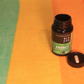 The Black Creek CBD Energy Capsules atop a colorful beach towel with one capsule sitting in the bottle's black cap
