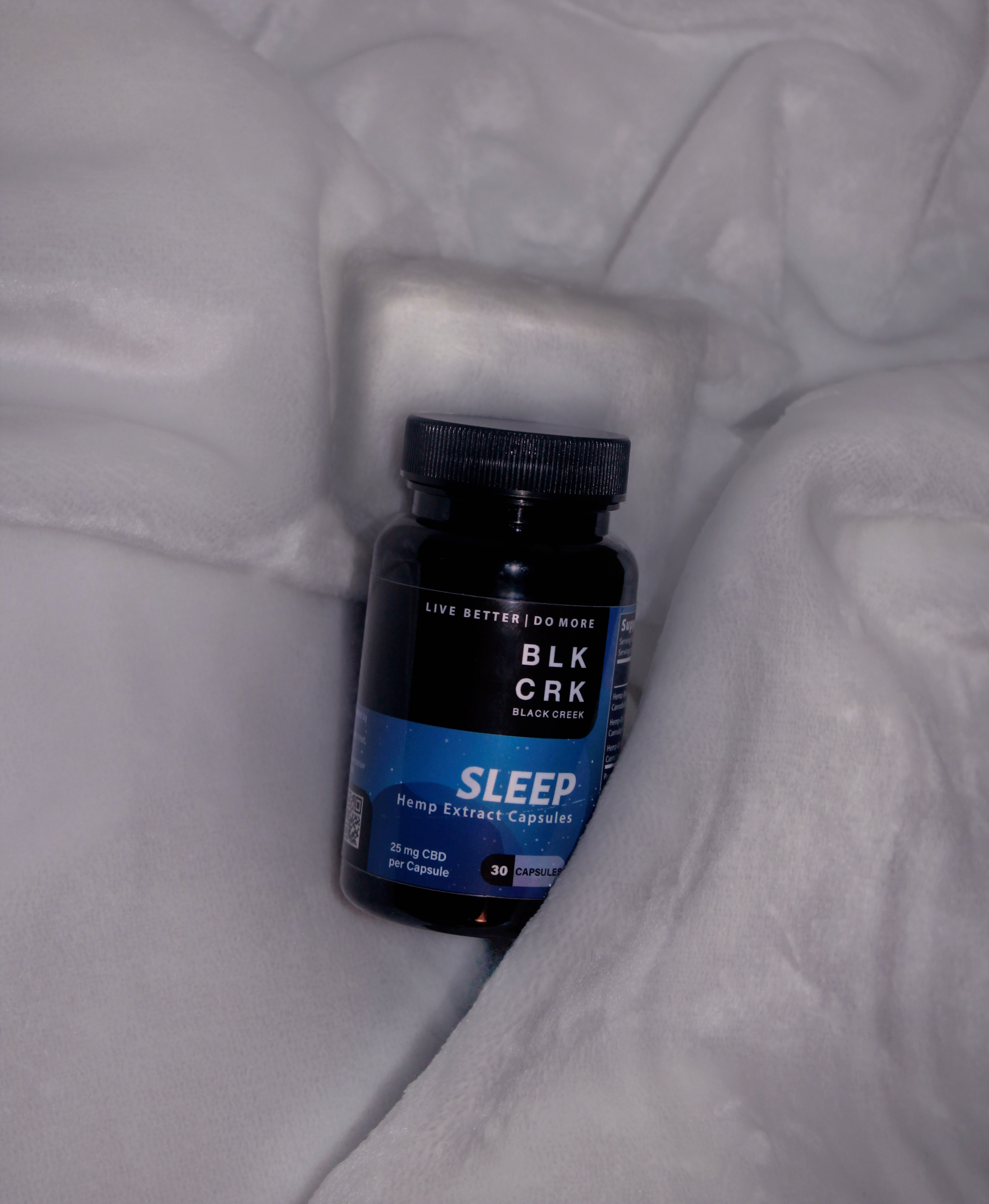 The Black Creek CBD Sleep Capsules lying in a white blanket