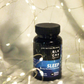 The Black Creek CBD Capsules on a white sheet with shiny fairy lights all around it