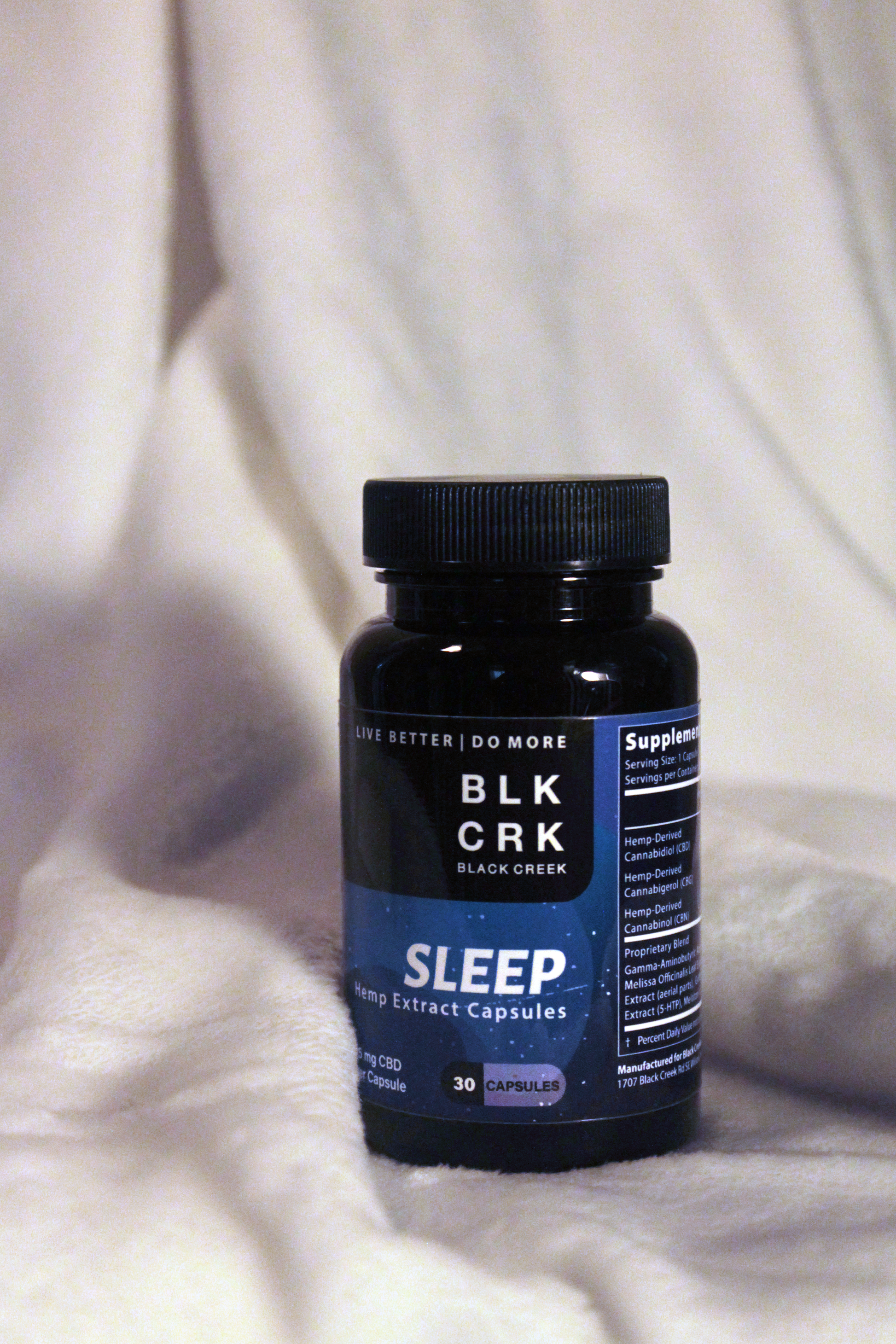 A picture of the Black Creek CBD Sleep Capsules in front of a cascading white blanket