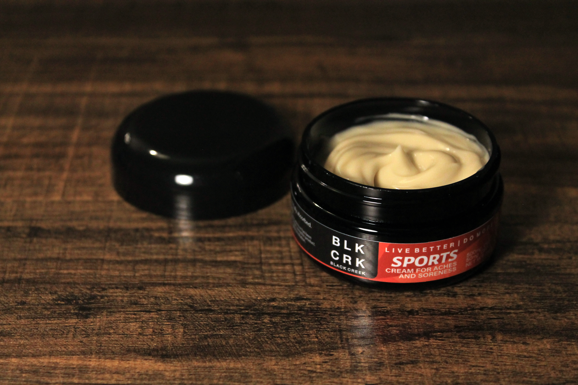 The Black Creek CBD sports cream sitting atop a wooden surface with the lid off to the side. 