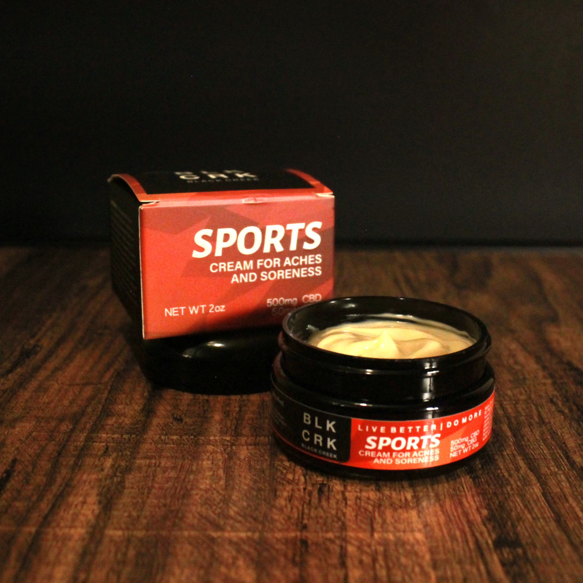 Black Creek CBD Sports cream with its box sitting on a wooden surface, black background